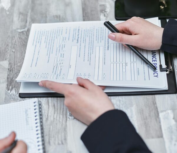 Free Close-up of hands analyzing insurance policy paperwork with pen on table. Stock Photo